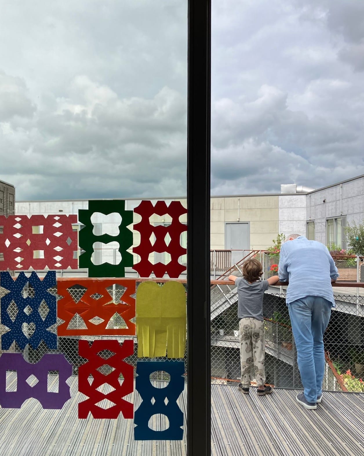 Verzieringen in een raam. Een kind en een volwassene staan met de rug naar de camera en kijken naar beneden.