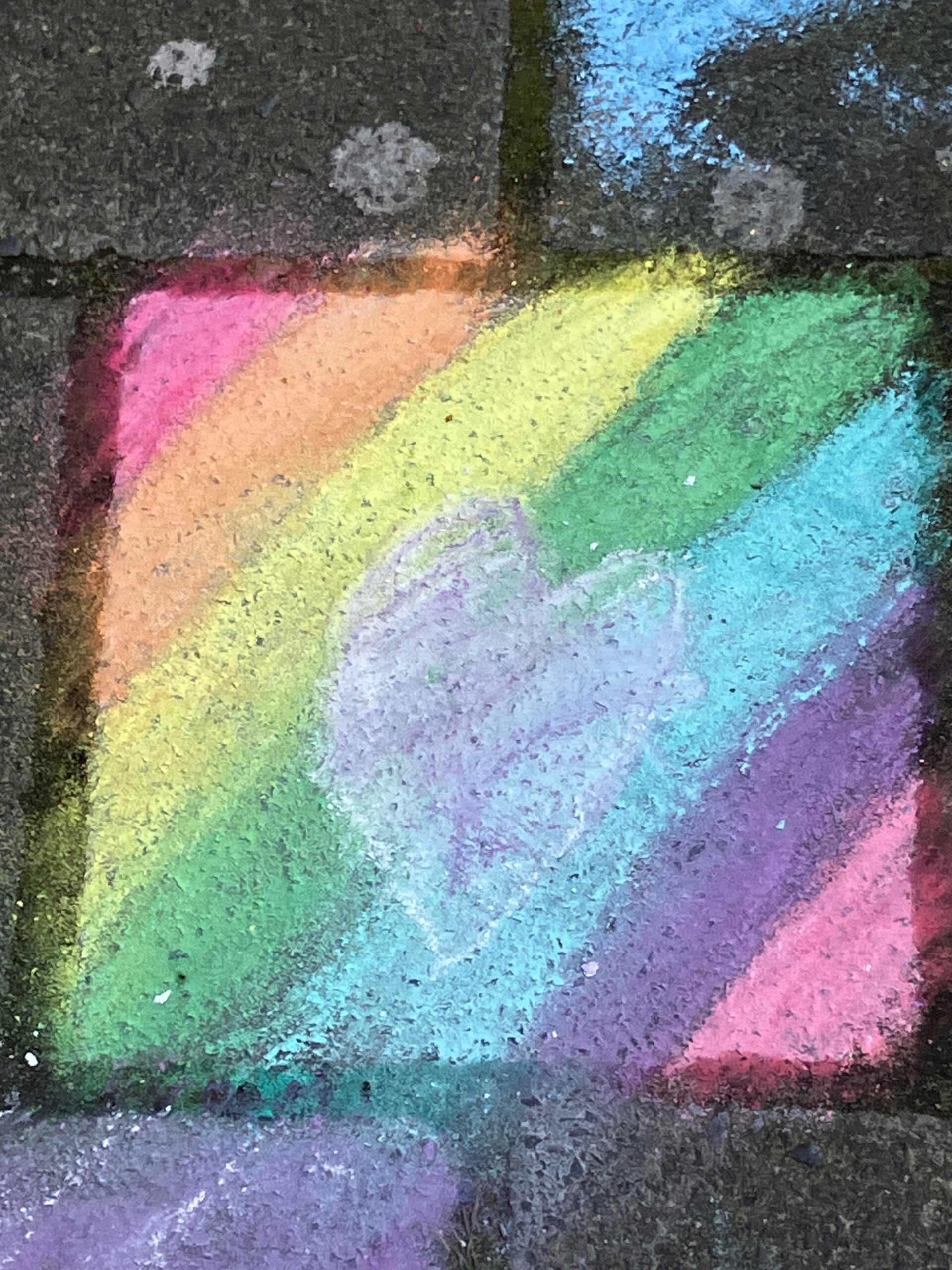 Een stoeptegel met regenbogenkleuren en een hartje