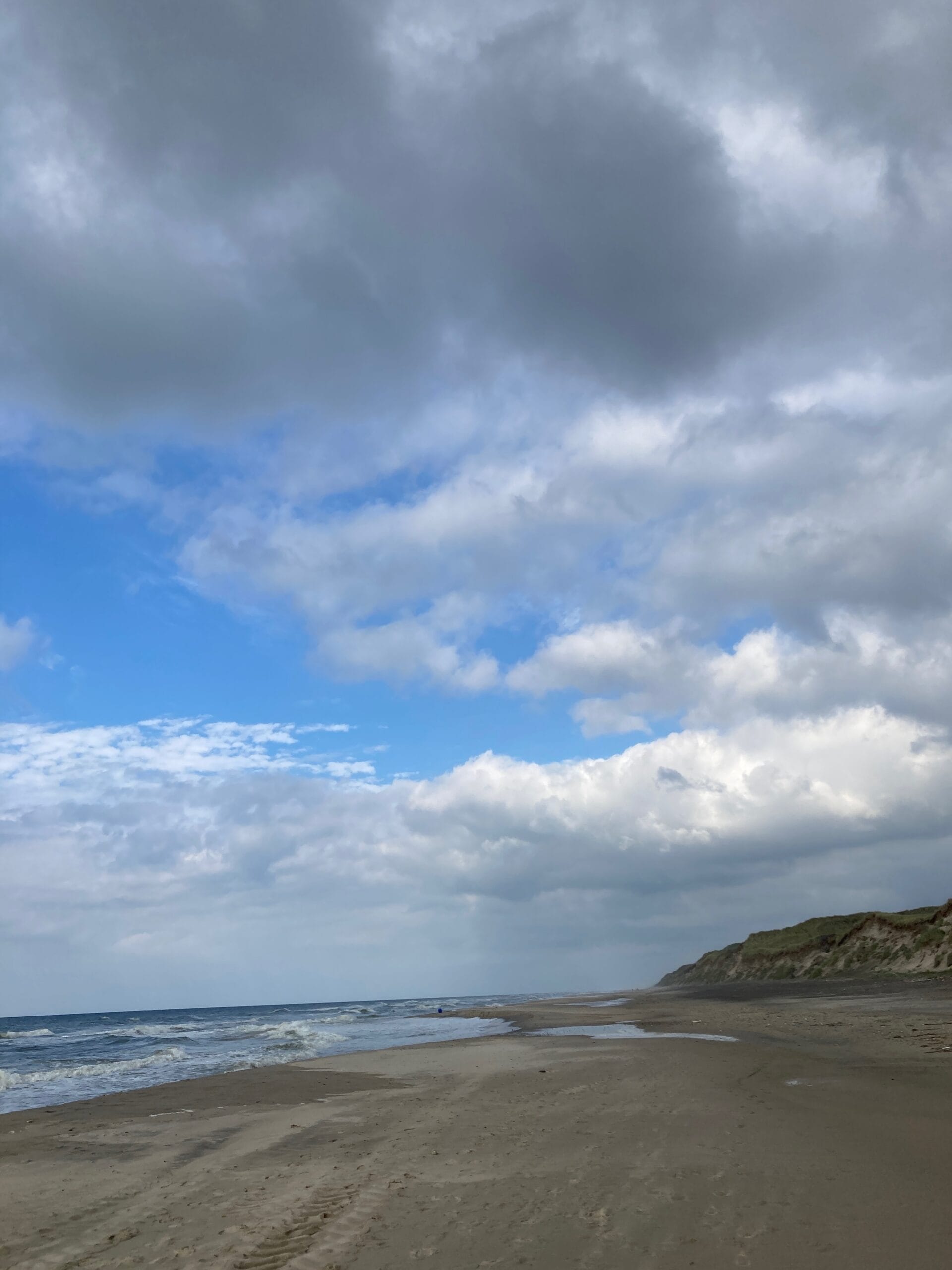 Bewolkte hemel met grijze hemel en strand eronder.